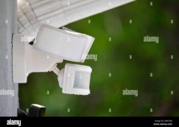 Motion sensor with light detector mounted on exterior wall of private ...