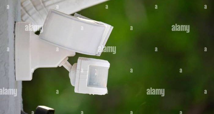 Motion sensor with light detector mounted on exterior wall of private ...